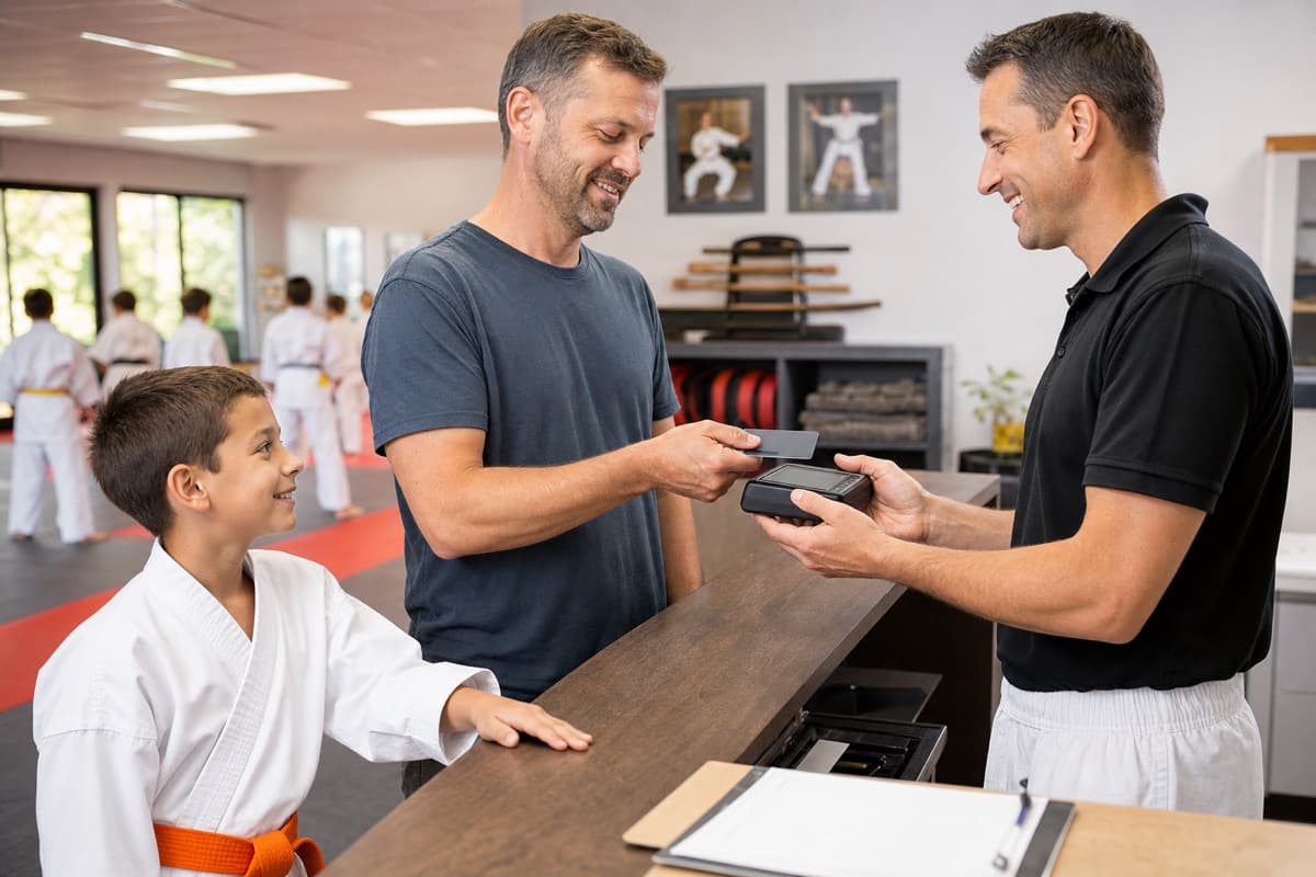 A parent paying karate tuition at the dojo front desk after class