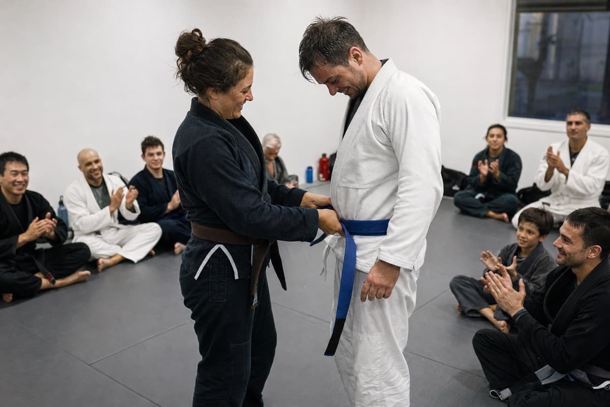 A Brazilian Jiu-Jitsu instructor awarding a student a blue belt after class